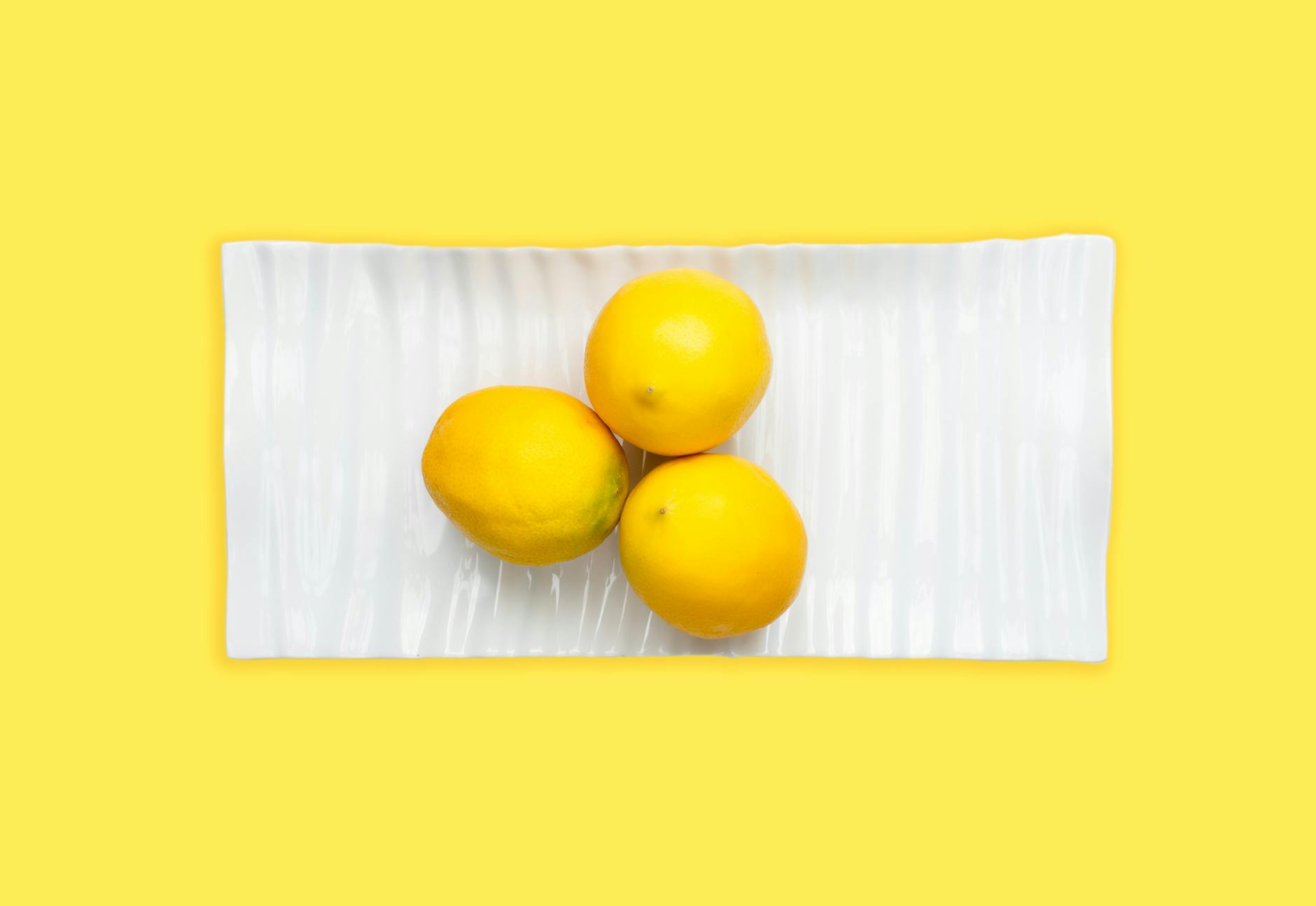 Ein blauer Vibrator umgeben von Blumen und Orangenscheiben auf gelbem Hintergrund, symbolisiert Sinnlichkeit und Erfrischung inmitten von Stress